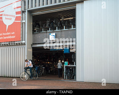 Haarlem, Paesi Bassi - 20 AGO 2018: Haarlem stazione ferroviaria centrale ingresso da Kennemerplein 6 street con l uomo e la donna accanto all'ingresso del parcheggio in bicicletta Foto Stock