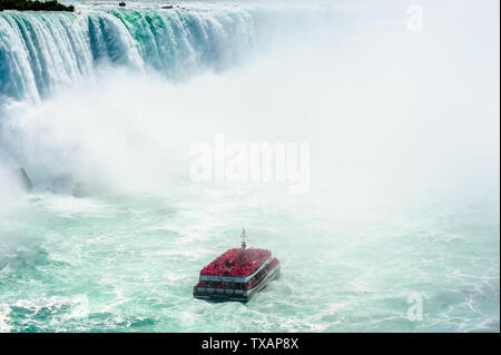 Cascate del Niagara, Canada - 27 agosto 2017: un tour in barca piena di passeggeri in rosso raincoats ottiene vicino alle cascate di Horseshoe. Foto Stock