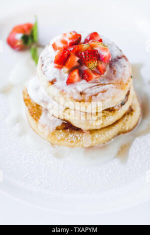 Frittelle di fragole con panna acida su sfondo bianco di close-up Foto Stock
