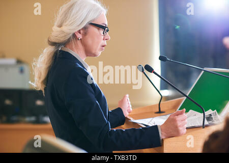 Coppia elegante delegato femmina in tuta parlando nel microfono Foto Stock