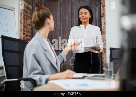 Ritratto di sorridere mixed-gara imprenditrice portando i documenti a femmina boss, spazio di copia Foto Stock