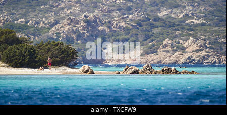 Un giovane non identificato sono a prendere il sole sulla bellissima spiaggia di Cavalieri (Spiaggia di Cavalieri) bagnata da un turchese mare chiaro. Arcipelago della Maddalena Foto Stock