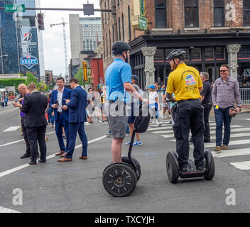 Ventilatori a piedi lungo Broadway e due uomini su Segway PT due ruote trasportatore personale a NFL Draft 2019 Nashville Tennessee negli Stati Uniti. Foto Stock