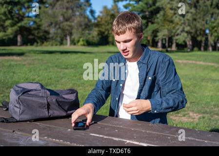 Sconvolto adolescente seduti ad un tavolo da picnic in un parco tutto da solo. Foto Stock