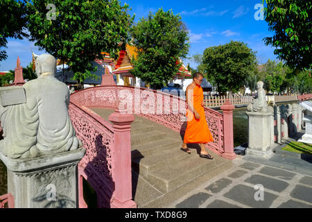 Un monaco buddista passa al di sopra di un elaborato di klong (canale) ponte di motivi di Wat Benchamabophit (chiamato anche tempio in marmo) a Bangkok, in Thailandia Foto Stock