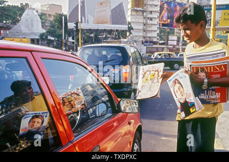 Ragazzo vendita di film di Bollywood riviste al traffico lo svincolo, Mumbai, Maharashtra, India, Asia Foto Stock