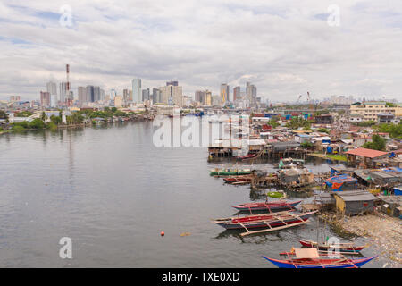 Baraccopoli di Manila sullo sfondo di una grande città. Case e barche degli abitanti poveri di Manila. Abitazione poveri nelle Filippine. Il contrasto gli strati sociali. Foto Stock