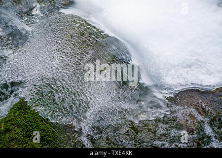 Un sottile strato di ghiaccio sul flusso in Tianchi Scenic Area in Tianshan, Xinjiang in inverno delinea la forma del flusso d'acqua. Foto Stock