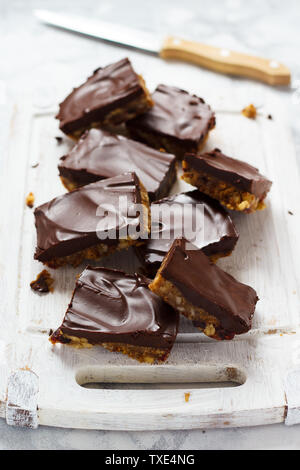 Materie barrette di cioccolato con noci e frutta secca. Sfondo bianco. Foto Stock