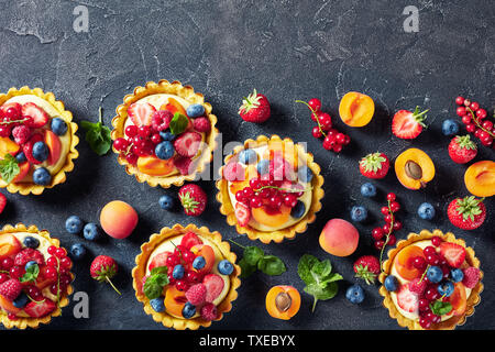 Close-up di estate dolci francesi - pasticcini con crema di limone ripieno di panna e rabboccato con lamponi, albicocche, mirtillo, fragola, ribes rosso Foto Stock