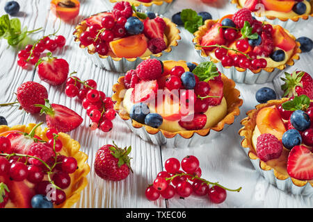 Close-up di francese dessert - crostate con crema di limone ripieno di panna e rabboccato con lamponi, albicocche, mirtillo, fragola, ribes rosso e fresco Foto Stock