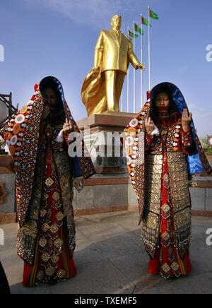 Due spose turkmeno in costumi tradizionali pagare il loro rispetto alla principale placcato oro monumento dell ex Presidente turkmeno Saparmurat Niyazov in Aşgabat, Turkmenistan il 11 maggio 2007. Tutte le coppie appena sposate devono visitare questo monumento. (UPI foto/Anatoli Zhdanov) Foto Stock