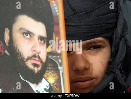 Un ragazzo iracheno assiste le preghiere del venerdì, come egli detiene un ritratto del chierico sciita Muqtada al-Sadr, nella roccaforte sciita di Sadr City a Baghdad, Iraq il 20 febbraio 2009. (UPI foto/Ali Jasim) Foto Stock