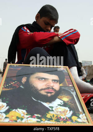 Un ragazzo iracheno assiste le preghiere del venerdì, come egli si siede da un ritratto del chierico sciita Muqtada al-Sadr, nella roccaforte sciita di Sadr City a Baghdad, Iraq il 20 febbraio 2009. (UPI foto/Ali Jasim) Foto Stock