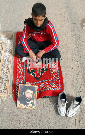 Un ragazzo iracheno assiste le preghiere del venerdì, come egli si siede da un ritratto del chierico sciita Muqtada al-Sadr, nella roccaforte sciita di Sadr City a Baghdad, Iraq il 20 febbraio 2009. (UPI foto/Ali Jasim) Foto Stock