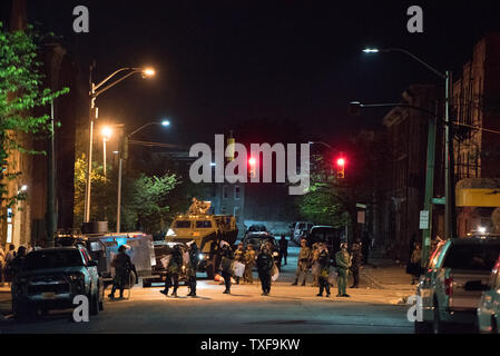 La polizia di tumulto linea di marcia fino con militare veicolo di soccorso mentre i cittadini locali spinto al limite del 10 p.m. coprifuoco a Baltimore, Maryland il 28 aprile 2015. Le proteste hanno eruttato dopo la morte di Freddie grigio. Foto di Ken Cedeño/UPI Foto Stock