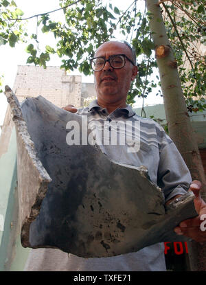 In una giornata che ha visto non colpisce le bombe a Beirut della periferia meridionale di un residente vi detiene una parte di una bomba israeliana sulla luglio 22, 2006. Oggi israeliano piani di guerra ha messo k.o. televisione e telefono cellulare di trasmissione nella parte del paese. Come la guerra infuria nel sud del Libano di decine di migliaia di cittadini stranieri sono stati evacuati dalle navi di Cipro. Oltre 300 libanesi, soprattutto civili sono morti poiché il conflitto ha cominciato il 12 luglio, dopo lo Hezbollah i guerriglieri hanno rapito due soldati israeliani e ucciso altri 7. UPI (foto) Foto Stock