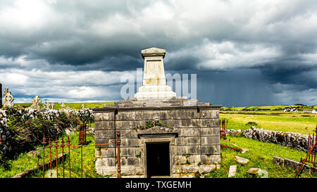 Il mausoleo di pietra della chiesa medievale di Killilagh nel villaggio di Doolin, meraviglioso contrasto tra il soleggiato e nuvoloso, con un cielo grigio Foto Stock