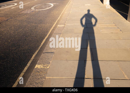 Punto di vista personale ombra di un uomo con le sue mani sulla testa di hips al tramonto di lasciare l'ufficio Foto Stock