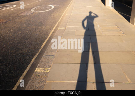 Punto di vista personale ombra di un uomo di graffiare la sua testa al tramonto di lasciare l'ufficio Foto Stock