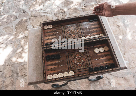 Una mano d'uomo rotoli dice all'inizio di un gioco del Backgammon. Un bordo del backgammon con gli intricati disegni. Foto Stock