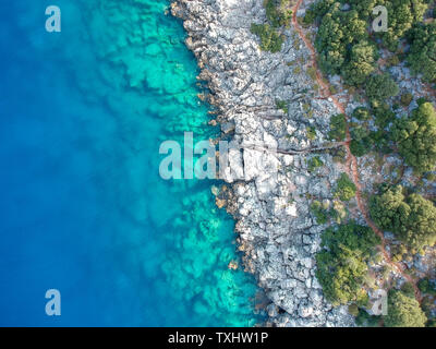 Vista diagonale da sopra di una bellissima costa rocciosa con acque blu cristallo. Via Licia sulla Costa turchese, Turchia Foto Stock