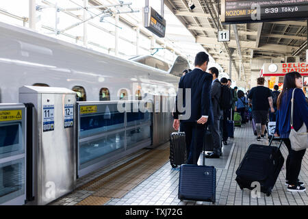 Kyoto, Giappone - 17 Aprile 2019: Stazione ferroviaria piattaforma con shinkansen e salaryman persone con bagaglio in attesa per i bagagli in macchina Foto Stock