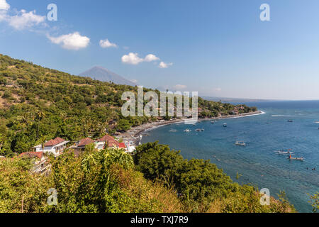 Vista del vulcano Agung dall'oceano. Villaggi, case tradizionali barche da pesca jukung intorno a. Amed, Karangasem Regency, Bali, Indonesia Foto Stock