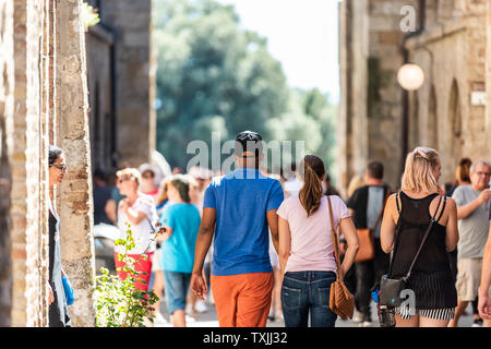 San Gimignano, Italia - 27 agosto 2018: indietro di molte persone e un paio di esplorare a piedi piccola e antica città medievale Borgo in Toscana Foto Stock