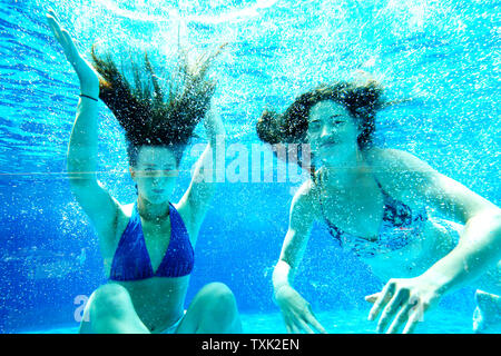 Gelsenkirchen (Germania). Il 25 giugno, 2019. Carla (l) e Luzie nuotare sotto l'acqua nel Gruga piscina esterna alle alte temperature estive e quindi raffreddare. Credito: Roland Weihrauch/dpa/Alamy Live News Foto Stock