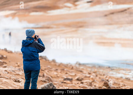 Hverir, Islanda - 16 Giugno 2018: Le calde fumarole con persone turista una donna a ricoprire guardando a vista con geyser in geotermia area spot da Myvatn lak Foto Stock