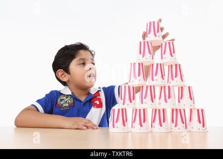 Ragazzo costruendo un tazze monouso house Foto Stock