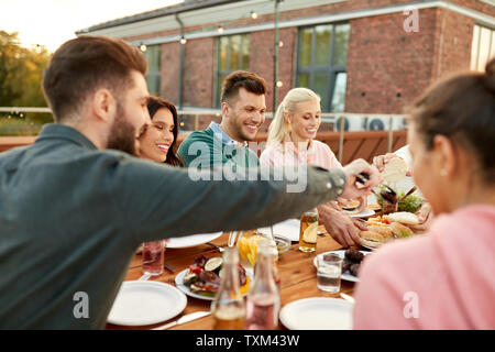 Gli amici di mangiare hamburger a cena sulla terrazza sul tetto Foto Stock