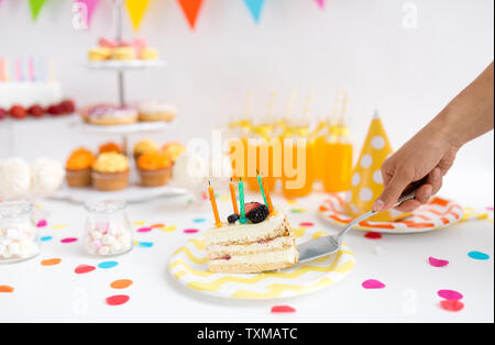 Mettendo mano pezzo di torta di compleanno su piastra Foto Stock