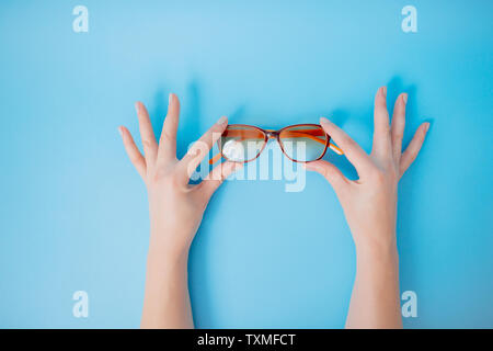 Mani femminili tenendo delicatamente i bicchieri su sfondo blu. Foto Stock
