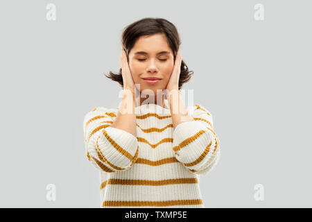 Donna felice in pullover di chiudere le orecchie con le mani Foto Stock