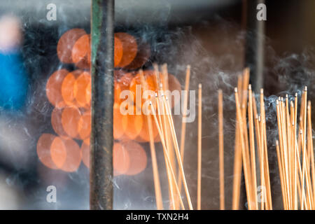 Kyoto, Giappone santuario del tempio di fumo di incenso fiamma ardente bastoni closeup con rosso arancio bokeh di fondo e nessuno Foto Stock