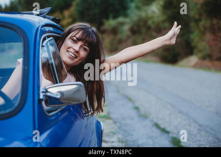 Donna alla guida, testa di incollaggio ed estrarre il braccio del finestrino Foto Stock