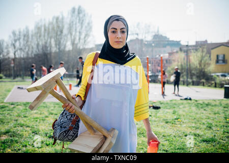 Classe Calisthenics presso palestra all'aperto, giovane donna che trasportano attrezzatura ginnica Foto Stock