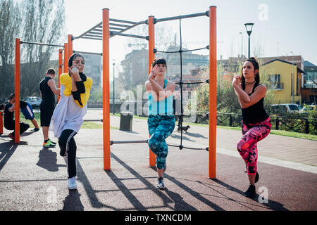 Classe Calisthenics presso palestra all'aperto, giovani donne in equilibrio su una gamba Foto Stock