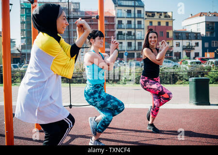 Classe Calisthenics presso palestra all'aperto, giovani donne in equilibrio su una gamba, vista laterale Foto Stock