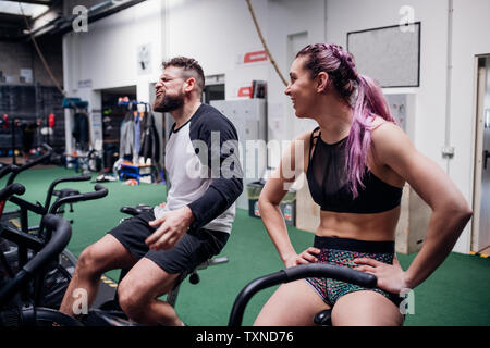 Esaurito giovane donna e uomo insieme di formazione su palestra cyclette, prendendo una pausa Foto Stock