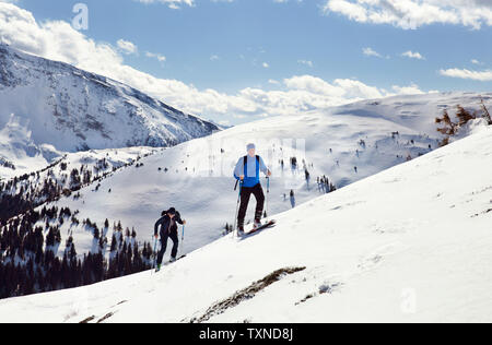 Coppia sci giovane nello spostamento verso l'alto coperta di neve montagna, Stiria, Tirolo, Austria Foto Stock