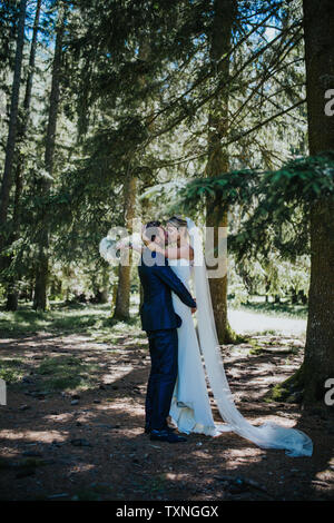 Romantico groom sollevamento sposa per kiss nel bosco Foto Stock