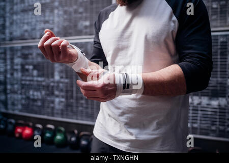 Uomo a mettere su handwrap in palestra Foto Stock