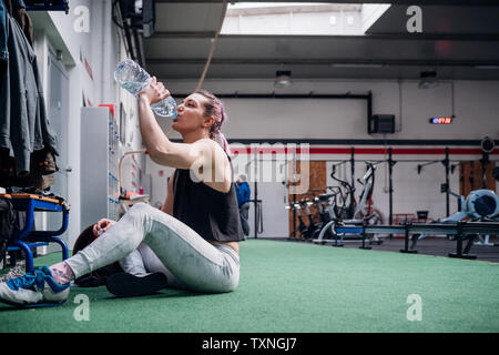 Giovane donna acqua potabile in palestra Foto Stock