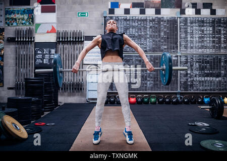 Giovane donna il sollevamento barbell in palestra Foto Stock