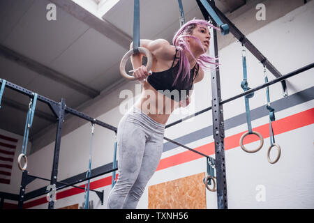 Giovane donna in equilibrio su anelli di ginnastica in palestra Foto Stock