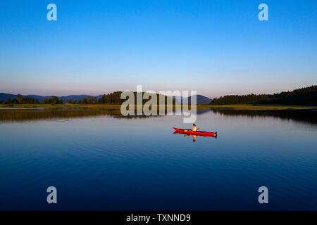 Antenna vista posteriore della donna atletica kayak al tramonto sul Lago di Cerknica, Slovenia, prese da fuco. Foto Stock