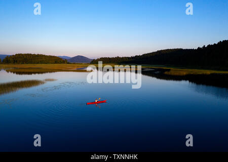 Antenna vista posteriore della donna atletica kayak al tramonto sul Lago di Cerknica, Slovenia, prese da fuco. Foto Stock